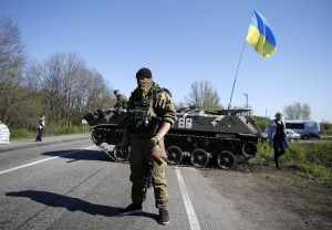 A Ukrainian soldier stands guard in front of an armoured personnel carrier at a checkpoint in the village of Malinivka, east of Slaviansk